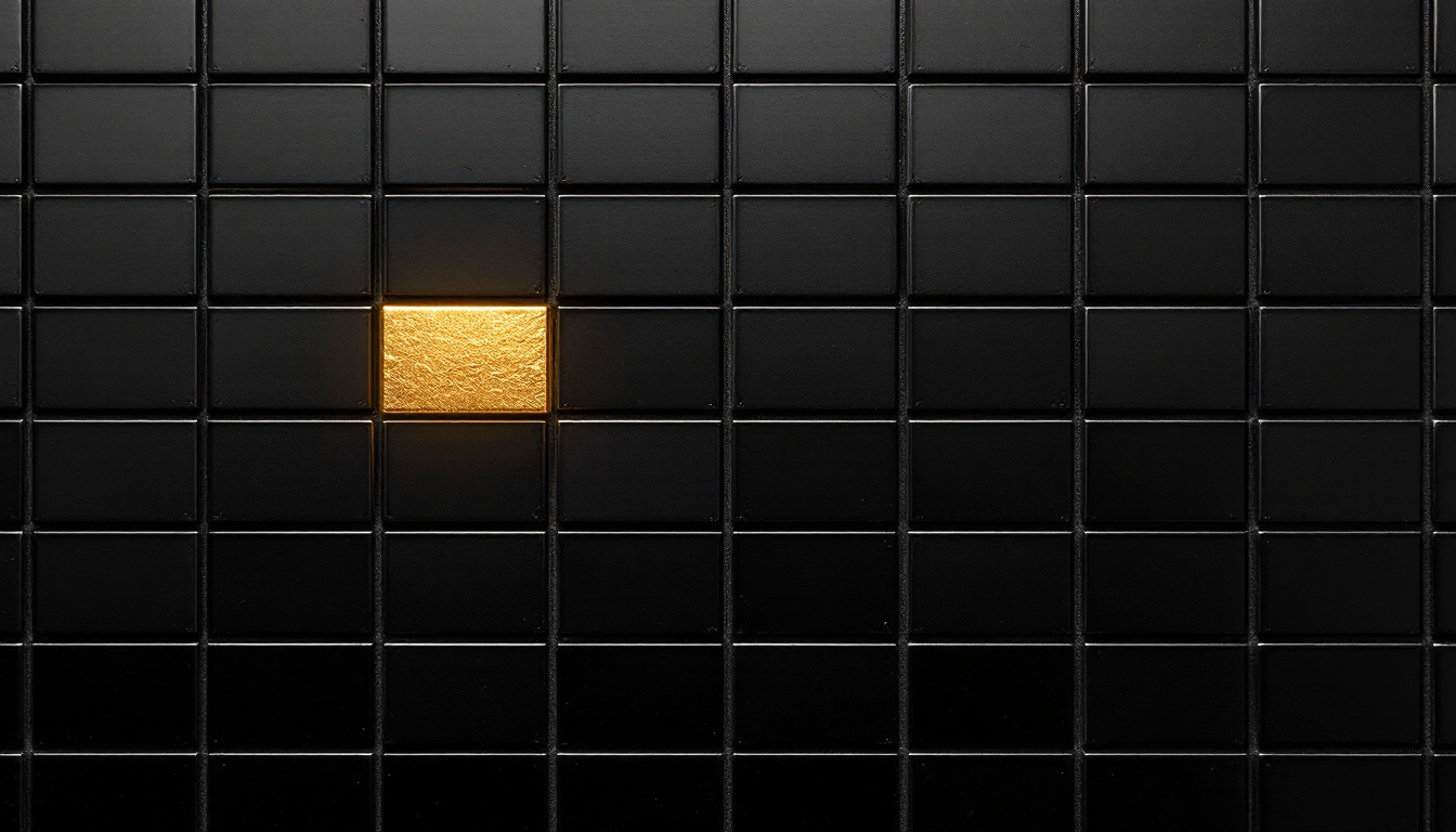 A wall-sized grid of small matte black tiles, one tile gilded in gold leaf catching a warm directional light.